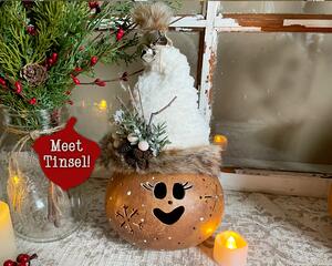 This image shows a Christmas Elf Decoration. It is made using a dried gourd. This elf's name is Tinsel and is wearing a handmade hat. 